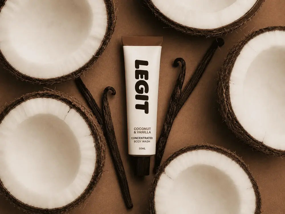 A tube of Legit Coconut & Vanilla among halved coconuts and vanilla pods